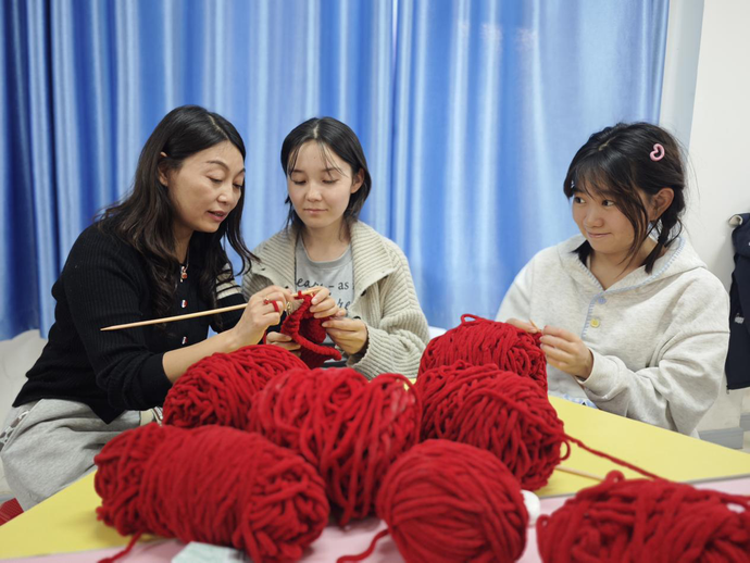 图为教师指导学生进行编织.png